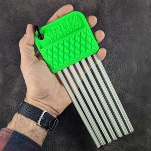 Green CRUX Original Gold Brush with long white bristles held in hand for gold prospecting bedrock cleaning.